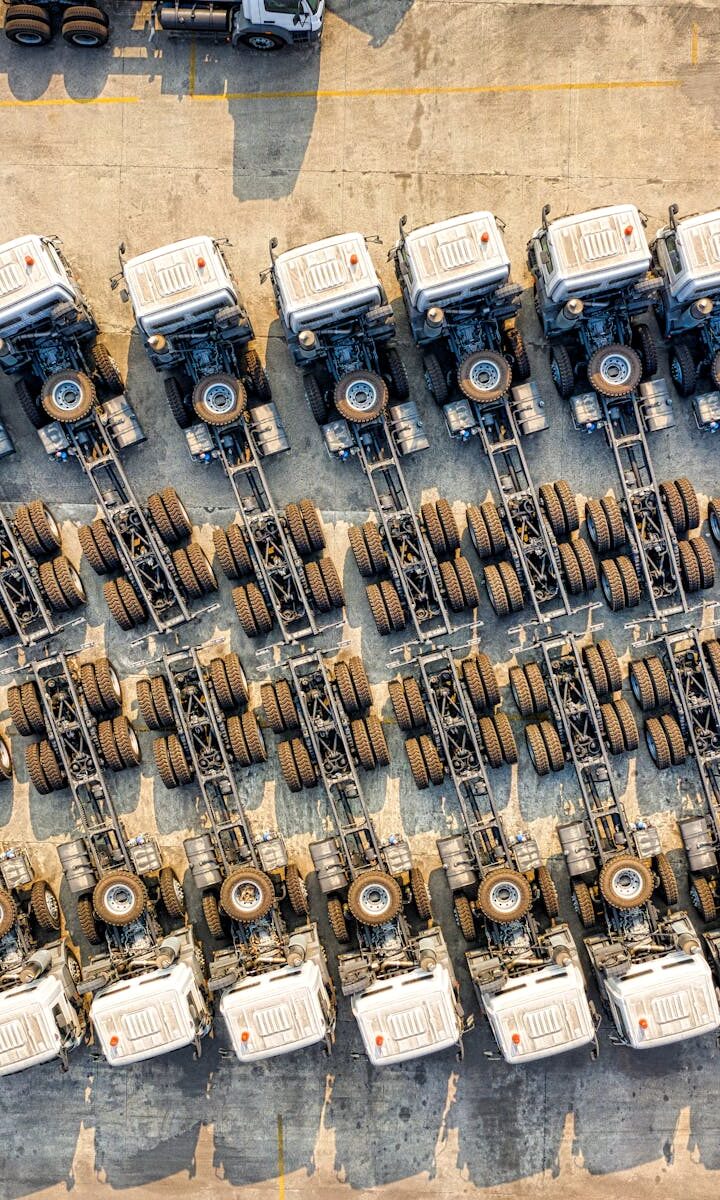pexels-photo-3245122-3245122 Aerial shot of multiple trucks parked in rows, highlighting transportation logistics.